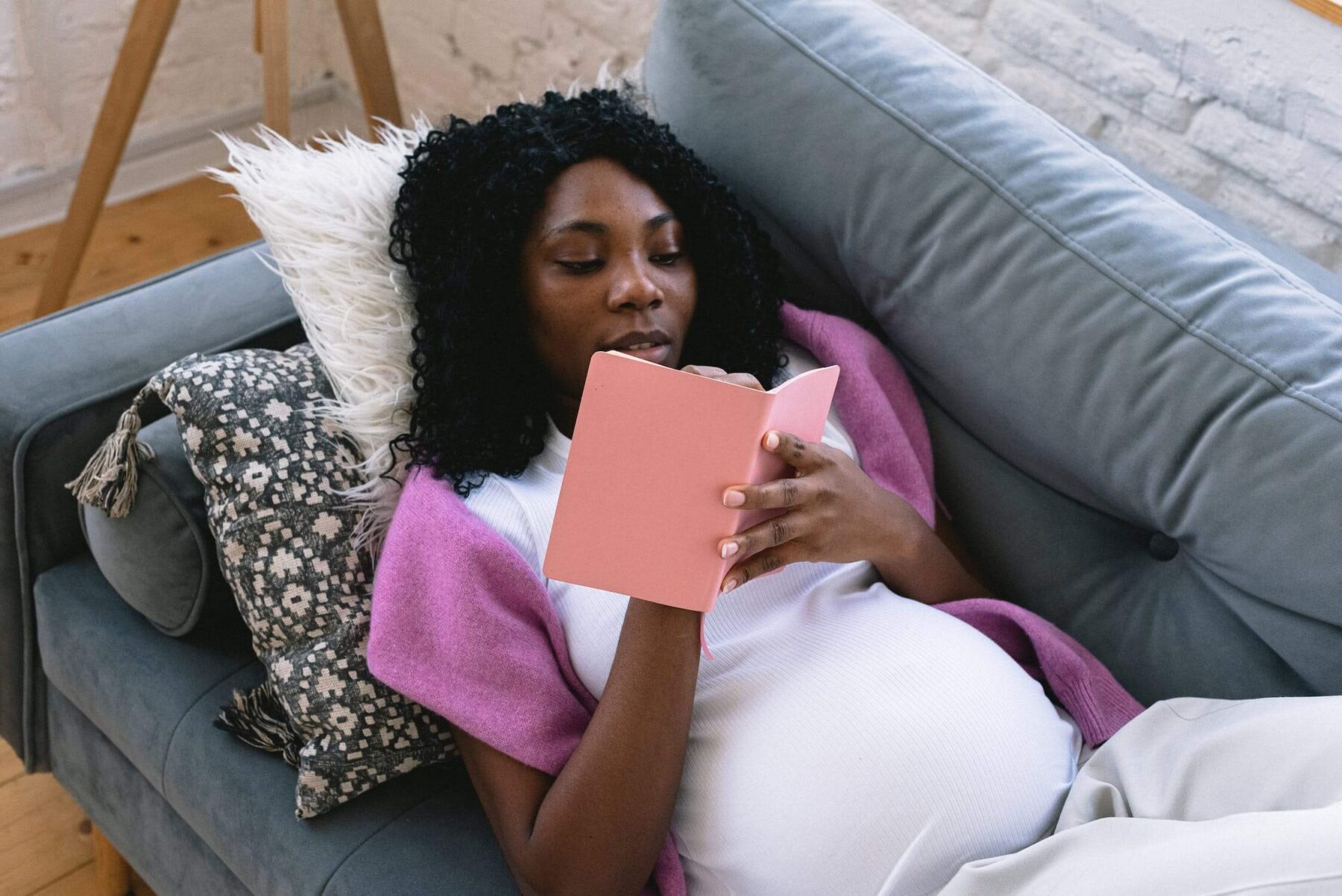 A pregnant woman laying on the couch and planning for postpartum using the 5-5-5 rule.